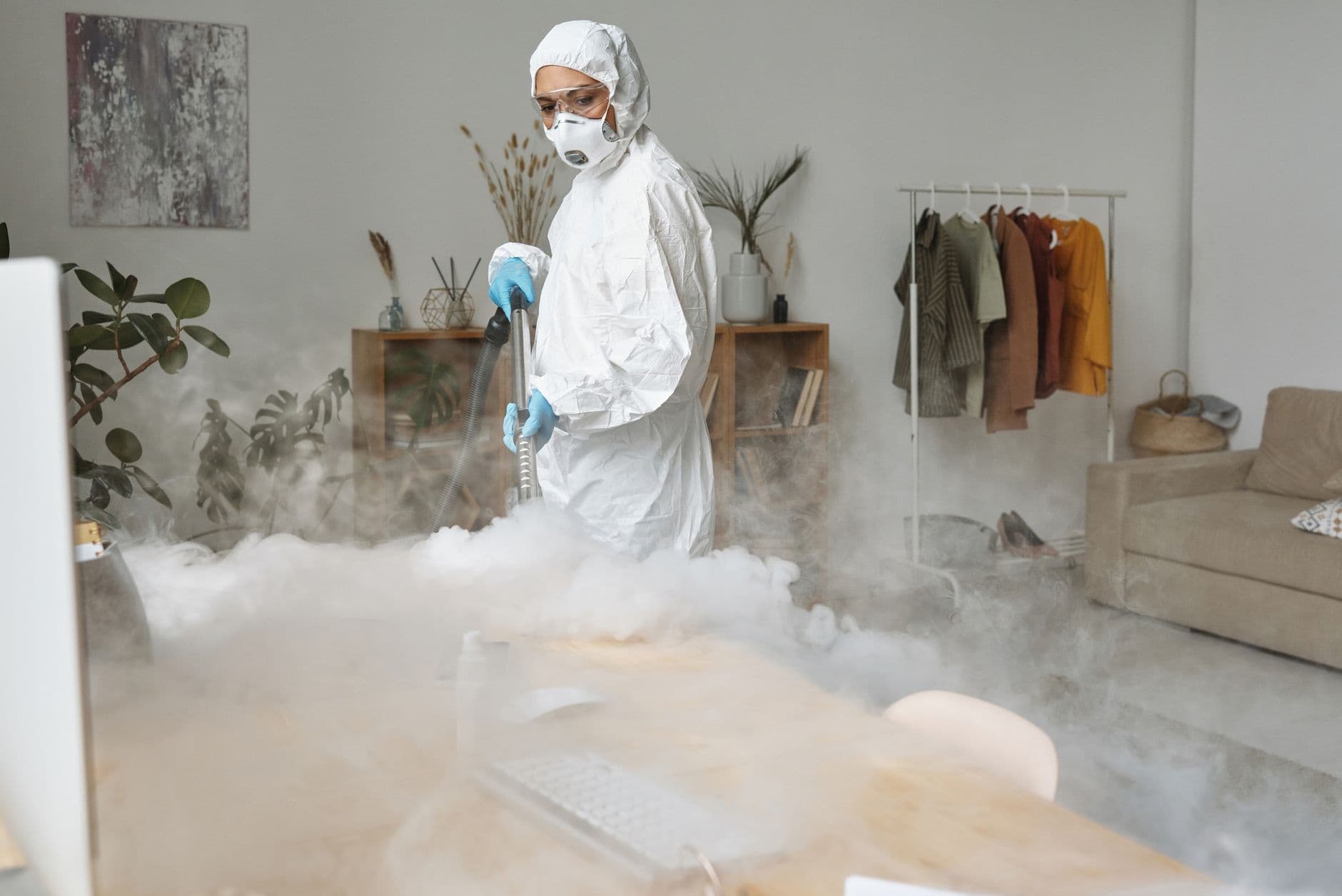 A professional specialist in a protective suit disinfecting surfaces in an industrial kitchen